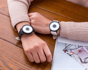 Close-up of minimalist couple watches with black and white leather straps on a wooden table