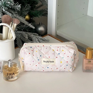 Detail of white quilted makeup bag featuring colorful polka dots and pink bow patterns