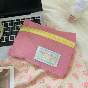 Pink mesh packing cube with yellow zipper detail shown in a lifestyle travel setup