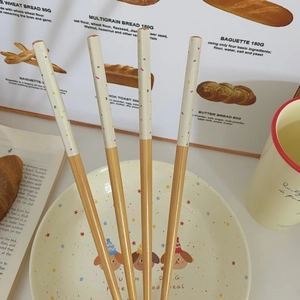 Close-up of bamboo chopsticks with colorful sprinkles design and a ceramic dog pattern plate