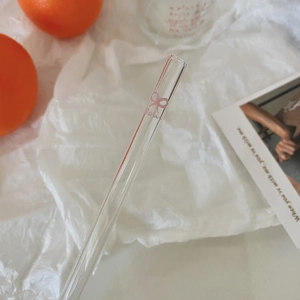 Detail of transparent glass straw with pink bow design and text in aesthetic setting