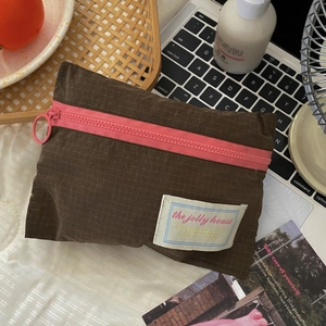 Close-up of brown travel organizer with pink zipper and signature woven label detail