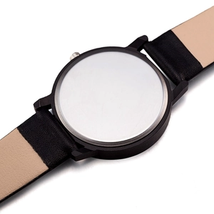 Close-up of matte black watch case with polished silver back and two-tone leather strap