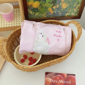 Pink fabric makeup bag with cat illustration in a woven basket lifestyle setting