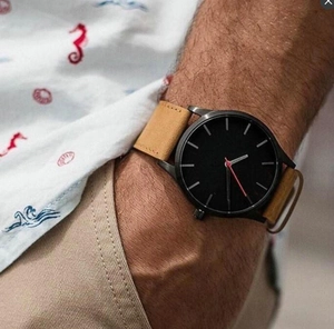 Men's minimalist watch with black dial, red second hand, and tan leather strap