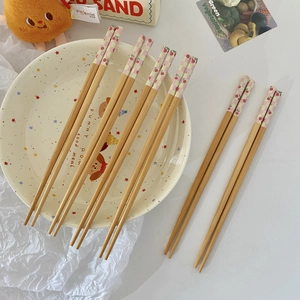 Detailed view of bamboo chopsticks with cherry patterns on a stylish ceramic plate