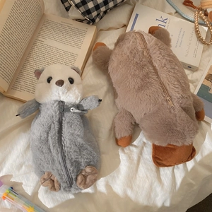 Detail of plush otter and platypus pencil cases on fabric with stationery accessories
