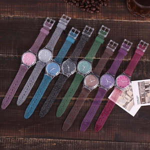 Set of nine colorful glitter quartz watches with transparent silicone straps on wood