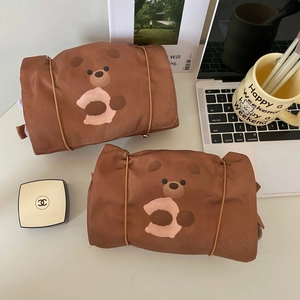 Macro view of two 4-in-1 detachable cartoon bear makeup bags on a tidy desk setup