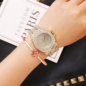 Close-up of gold iced-out watch and star cuff bracelet worn on model's wrist