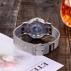 Minimalist silver mesh strap quartz watch with round metal dial on wooden desk