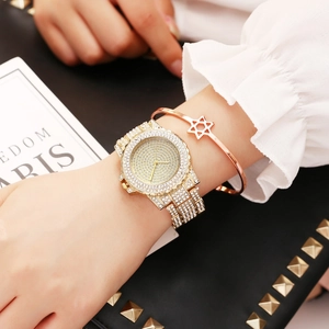 Close-up of a luxury women's gold watch with full diamond setting and matching star bracelet