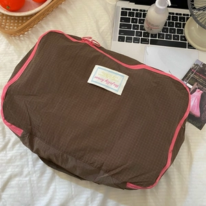 Close-up of waterproof brown travel organizer bag with pink zipper and woven label