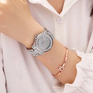 Close-up of luxury silver iced-out watch with a rose gold star bracelet on a wrist