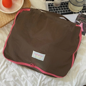 Detail of waterproof nylon travel organizer featuring pink contrast zippers and logo label
