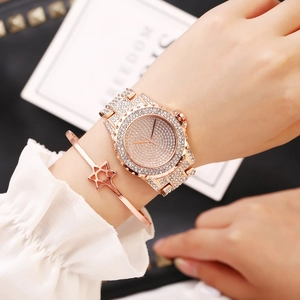 Close-up of rose gold iced-out watch and star bracelet set on woman's wrist