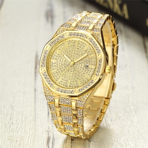 Macro shot of gold-tone iced out watch showing octagonal bezel and diamond-studded band