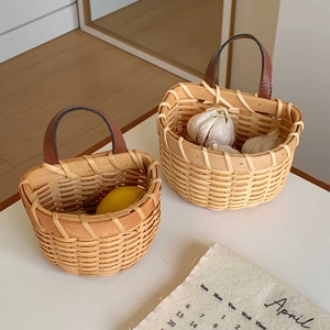 Detail of hand-woven wood baskets with leather handles and lemons for kitchen storage