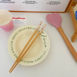 Detail of wooden chopsticks with pink cherry patterns and a cream ceramic dinner plate