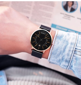 Macro detail of the quartz watch with black mesh strap and golden date window display