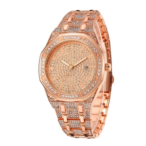 Macro detail of rose gold watch with crystal encrusted octagonal bezel and date window