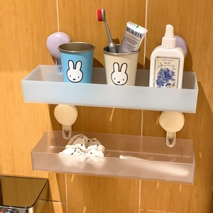 Detail of two frosted suction cup bathroom shelves mounted on tiles with toiletries