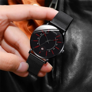 Close-up of black mesh strap watch with red markers and circular date window