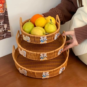 Three-piece nesting set of woven baskets with bear decor and handles on a dark wood table