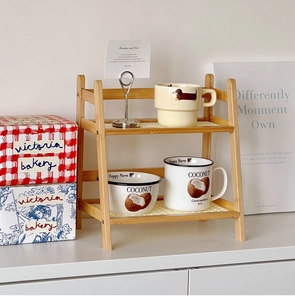 Detail of cream ceramic cups and bowls on a two-tier minimalist bamboo storage rack