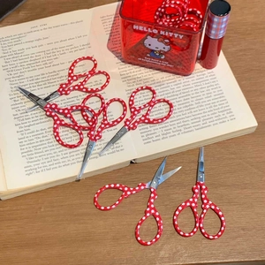 Detail of red and white polka dot pattern handles on small stainless steel craft scissors