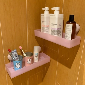 Detail of pink frosted bathroom shelves set showing suction mounting on wood tiles