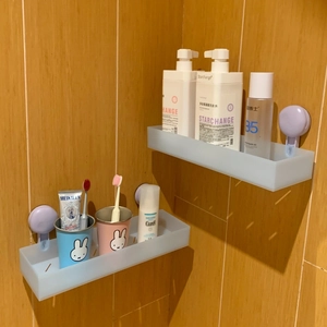 Close-up of wall-mounted frosted bathroom shelf with purple suction cup installation
