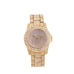 Detailed macro view of an iced-out gold watch featuring dense crystal pavé on the band