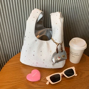Detail of white tote bag with silver star prints and Hello Kitty charm on wooden table