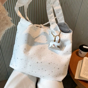 Detail of white canvas tote bag with silver stars and striped lining with tie closure