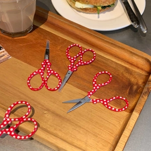 Close-up of mini red polka dot scissors on a wooden tray for DIY crafting projects