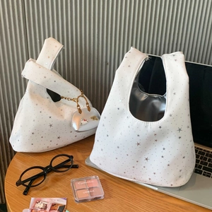 Detail of white star print tote bag with silver lining and heart charm for daily commute