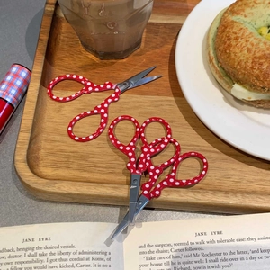 Close-up of small red polka dot scissors on a wooden tray for craft and sewing
