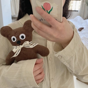 Cute brown plush teddy bear with a white bow tie shown in a cozy home setting
