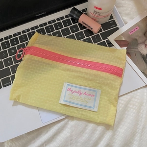 Close-up of yellow checkered nylon pouch with pink zipper on a laptop keyboard