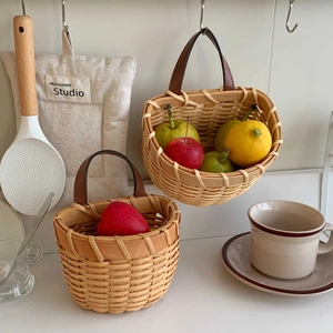 Set of two woven kitchen storage baskets with brown leather handles in a white kitchen