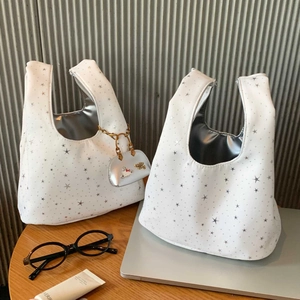 Detail of white tote bag with silver star patterns and metallic Hello Kitty charm