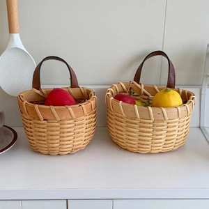 Close-up of woven ginger and garlic storage baskets with leather handles on a kitchen counter