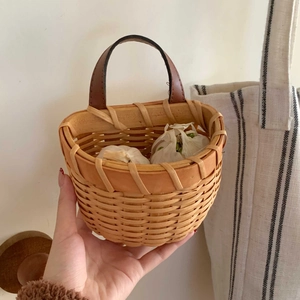 Close-up of hand-held woven bamboo basket with leather handle filled with fresh garlic