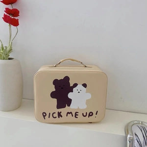Detail of cream bear makeup box with handle and Pick Me Up slogan in a home setting