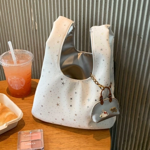 Detail of white star print tote bag with Hello Kitty charm in a cafe setting