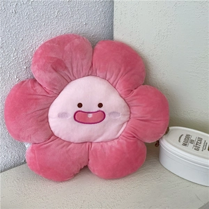 Cute pink flower plush pillow with a smiling face on a soft textured background