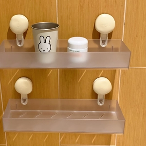 Detail of grey frosted wall-mounted shelf with vacuum suction cups on tiled surface