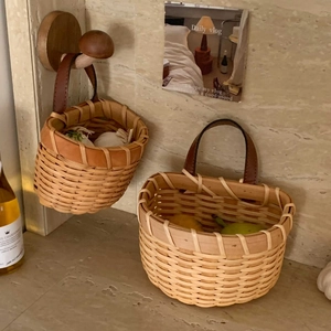 Detailed close-up of handmade woven baskets with dark brown leather handles for kitchen storage