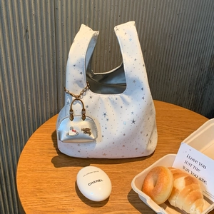 Detail of white nylon tote bag with silver star prints and mini bag charm accessory